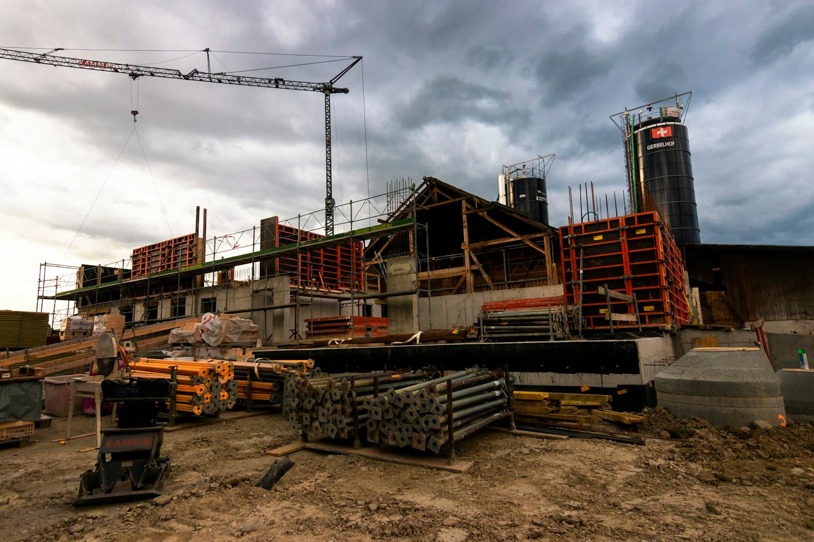 A construction site with a tower crane, formwork panels and stacked props